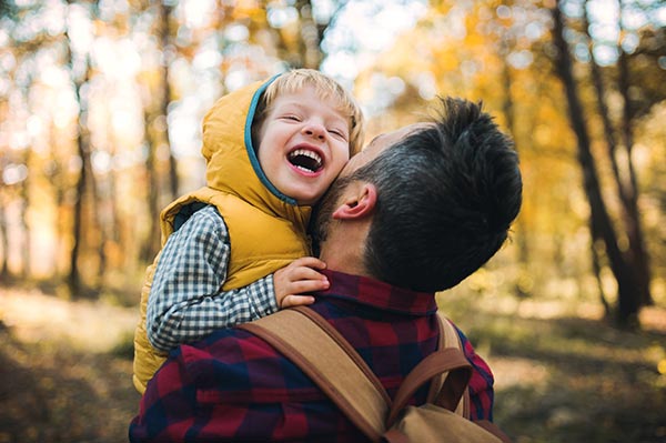 dad carrying laughing child in park